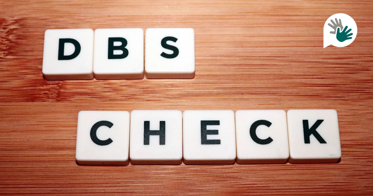 DBS check spelled out with letter tiles on a wooden surface.