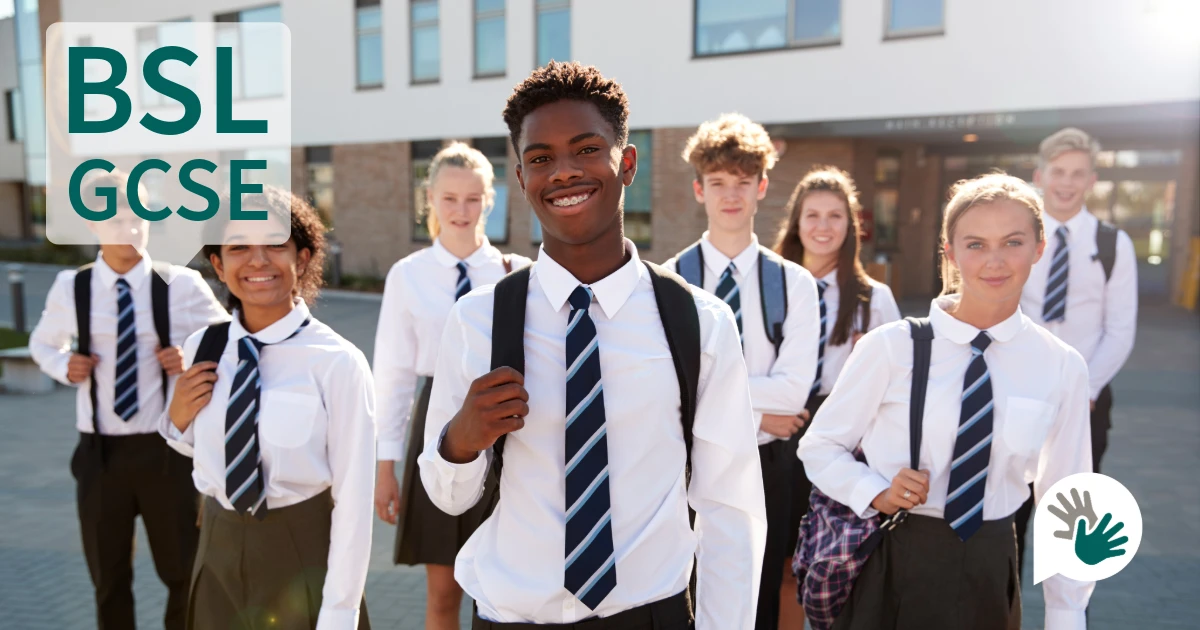Smiling secondary school students in uniform standing outside a school building, used to illustrate the introduction of the British Sign Language GCSE.