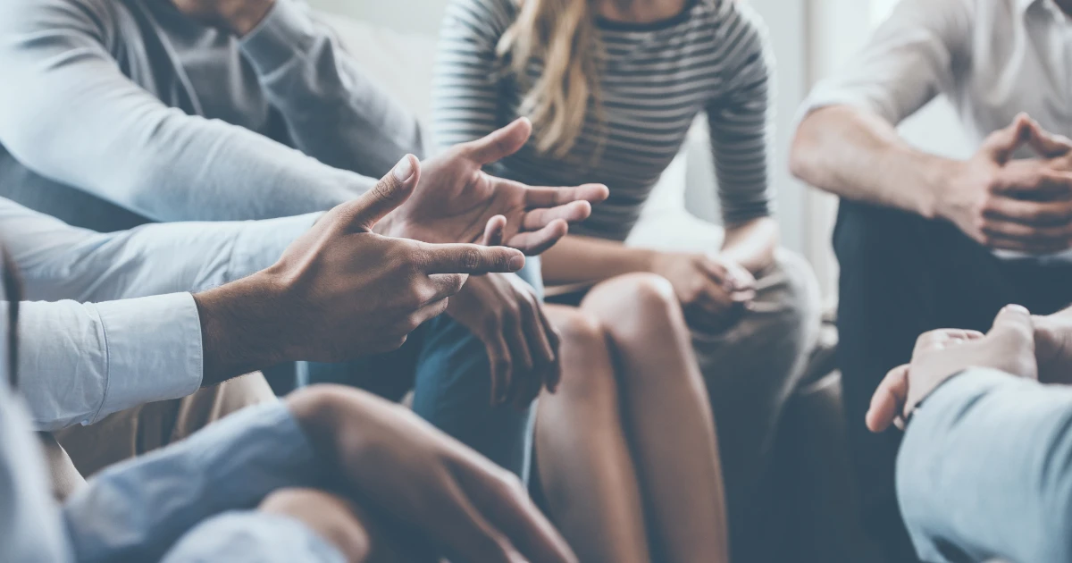 Close-up of people in discussion, gesturing with hands during a group conversation.